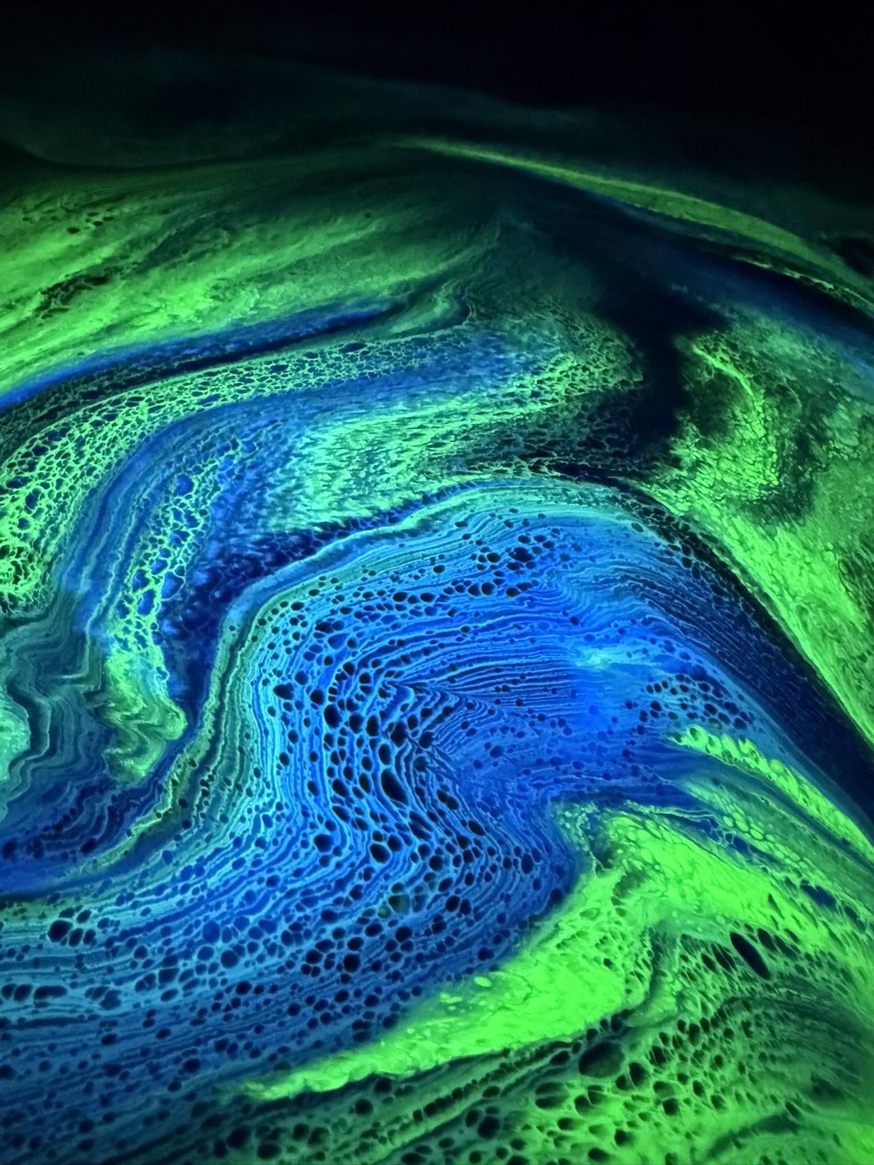 Close-up of a vivid green and blue art floor with glowing cell-like patterning