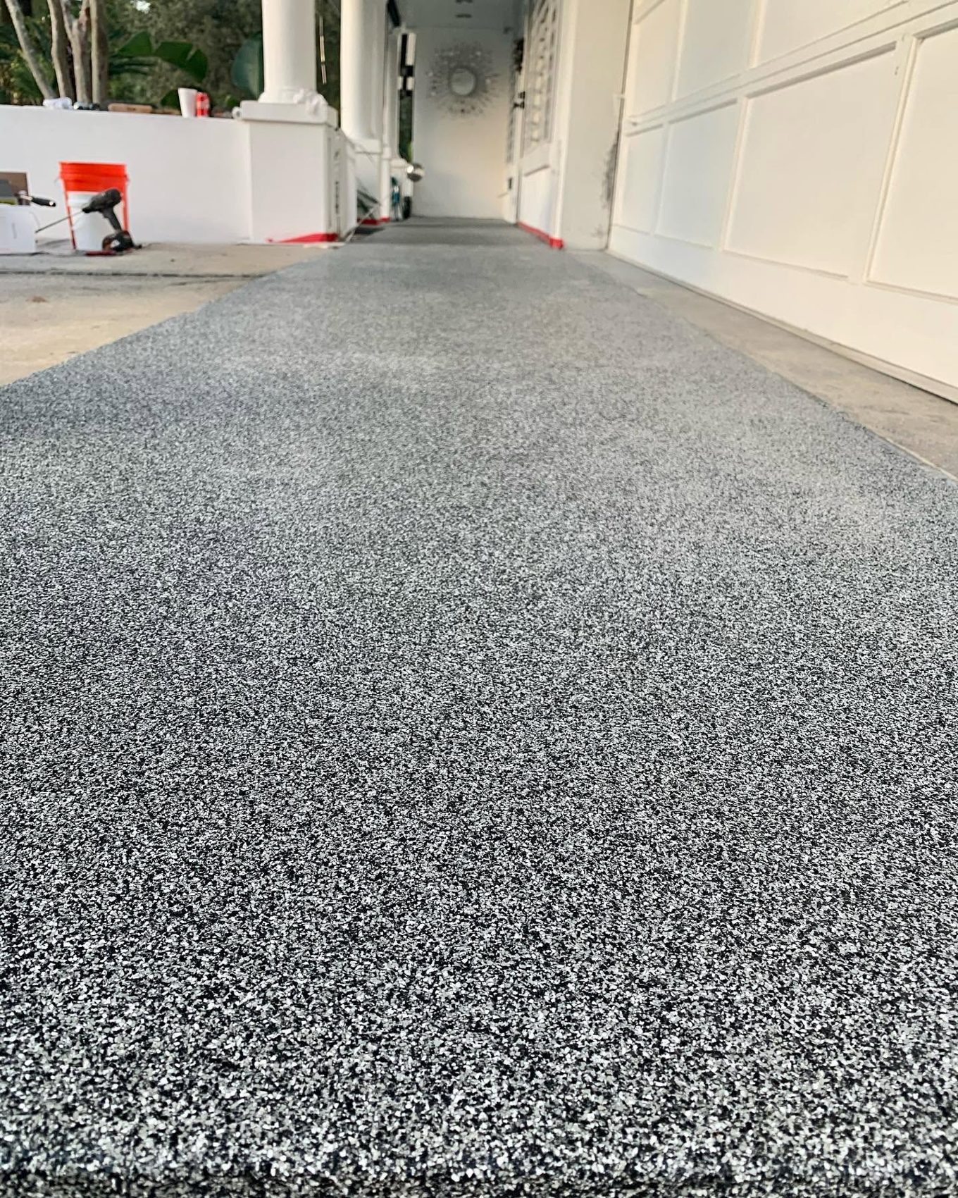 Gray and white broadcast flake coating on a long covered exterior walkway