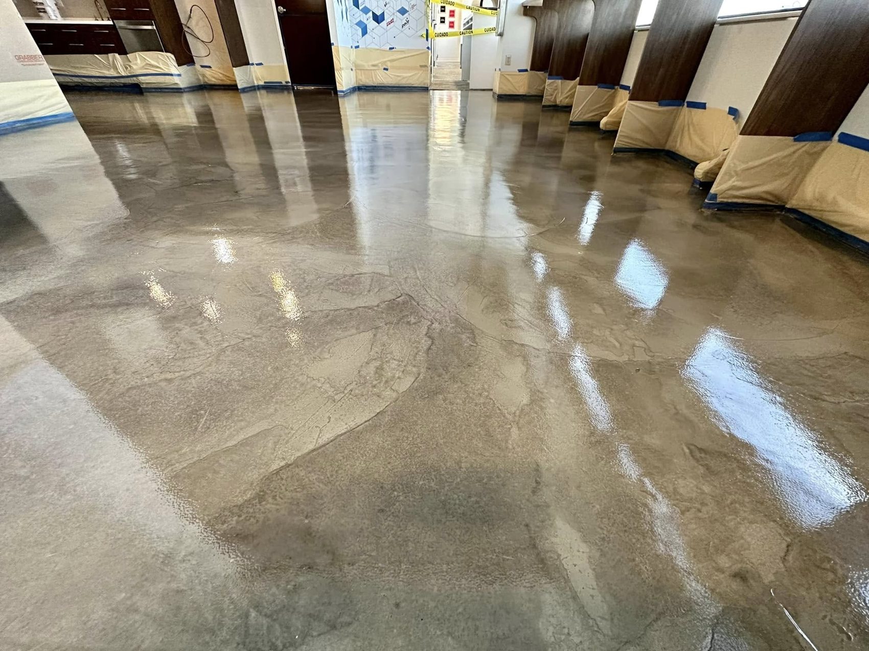 Gray and taupe metallic epoxy floor with a high-gloss finish in a commercial interior, walls still masked